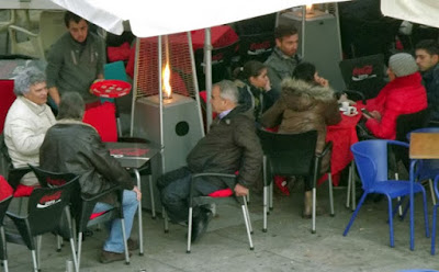 pessoas sentadas nas mesas da ribeira com aquecedor