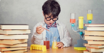 A young boy, donning a white lab coat and circular glasses, experimenting with his scientific toys.