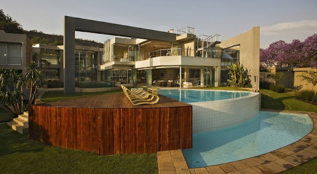 Photo of an amazing home with the pool and wooden deck as seen from the backyard