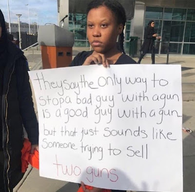 black teenaged girl holding a sign reading 'they say the only to stop a bad guy with a gun is a good guy with a gun but that just sounds like someone trying to sell two guns'