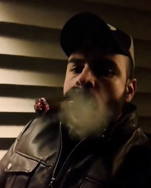 Sexy man blowing out smoke wearing black leather jacket cigar and mouth