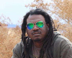 A black man in reflective sunglasses, a hoodie, and a tee shirt.