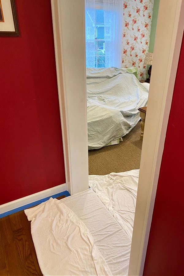 Sheets covering wood floor and sofa in an adjoining room