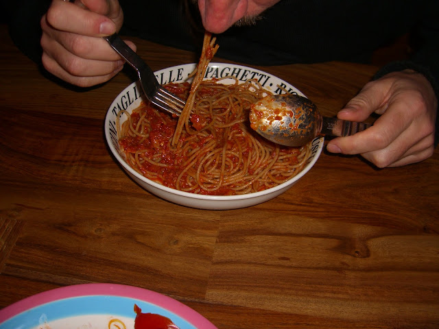 Foto van iemand die een bord spaghetti puttanesca eet