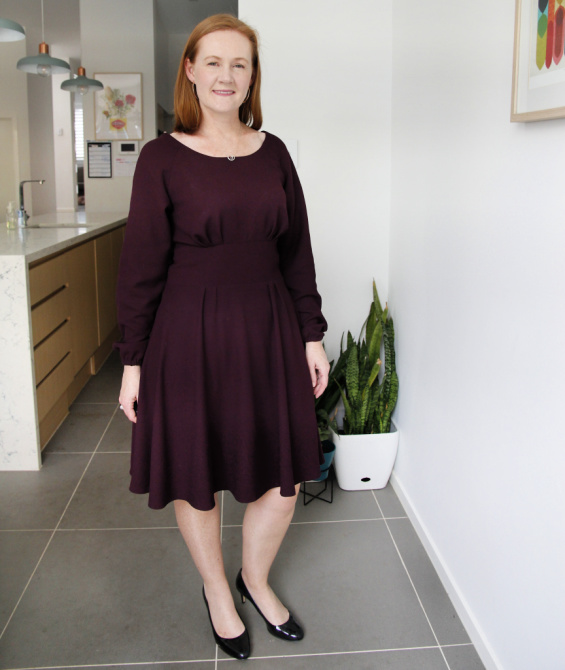 a photo of a white woman posing in a maroon dress