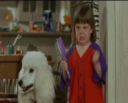 A classic gif. A young girl with a wonky fringed bob (reminiscent of my own childhood haircut) is angrily frustrated and waves a closed paper fan in her hand, at the air. She's also standing next to a dog, that is looking on.