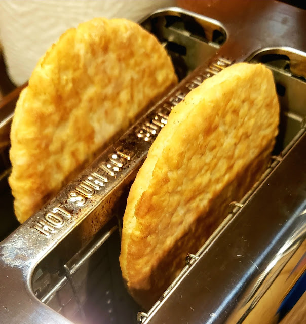 Two extra large toaster biscuits popped up in a stainless steel toaster