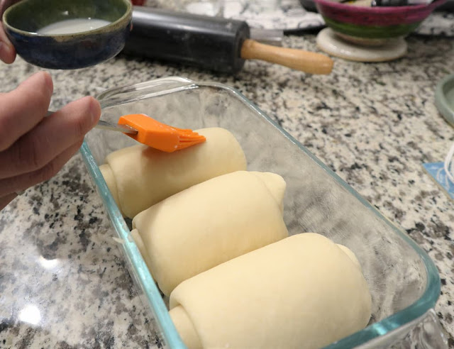 Brushing the top of each roll dough with milk