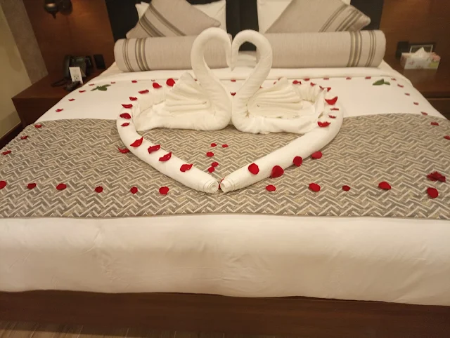Romantic bedroom decor with rose petals and swan towels on valentine's day by Yogh Hospitality Hotel in Suriname"