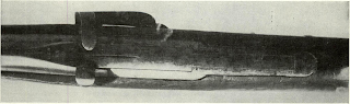 Long strip on top of Jenks carbine lifts up by hook thumbpiece to uncover trough for loading combustible cartridge. Hammer must be cocked by pulling on hook end. Gun was designed for Navy use.