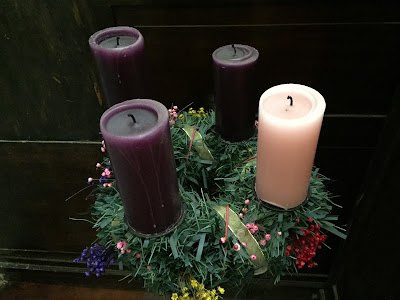 Arranjo com três velas roxas e uma vela rosa.