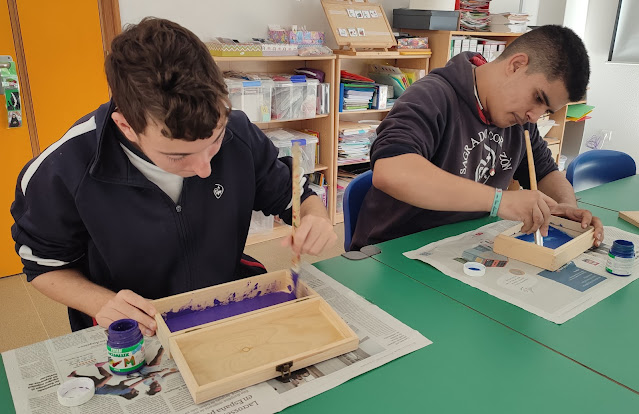 Alumnos pintando cajas de madera