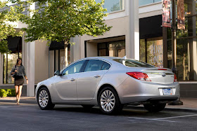 Silver 2012 Buick Regal E-Assist rear three-quarters view parked on city street with woman approaching