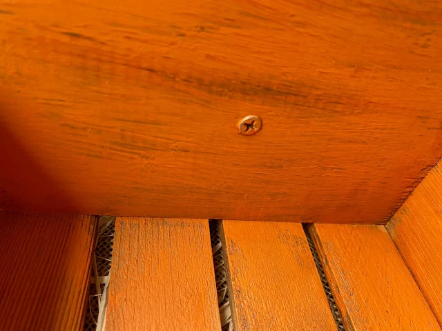 Photo of a screw attaching a tree stick stem being added to a pumpkin crate