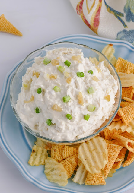 dip in a clear glass bowl on a blue plate with chips on the side.