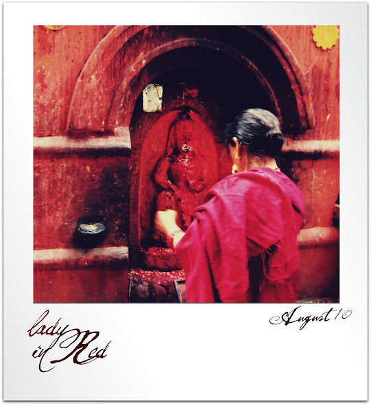 A woman in red gives thanks in Bhaktapur, Nepal. 