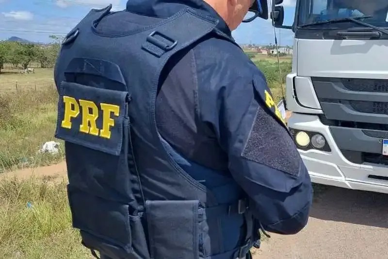 Agente da PRF em frente a um caminhão Mercedes-Benz Atego branco