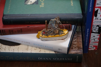 PIle of books and small wooden boat ornament
