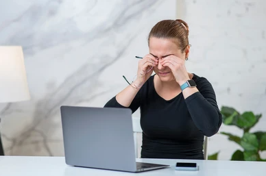 Woman rubbing her tired eyes in front of computer