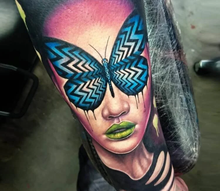 Tatuaje de un rostro a color con una mariposa tapando su mirada