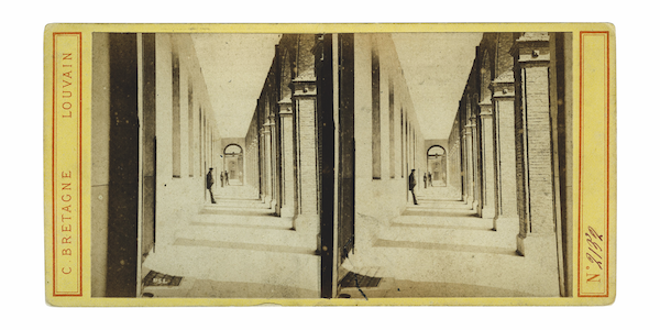 Early twentieth century picture representing one of the corridors adjacent to the central court. Halfway the corridor a man is leaning to the wall. At the back two more figures are visible. The photograph is duplicated and placed on a piece of yellow paper on which the following inscriptions can be found: N°2132, C. Bretagne, Louvain.