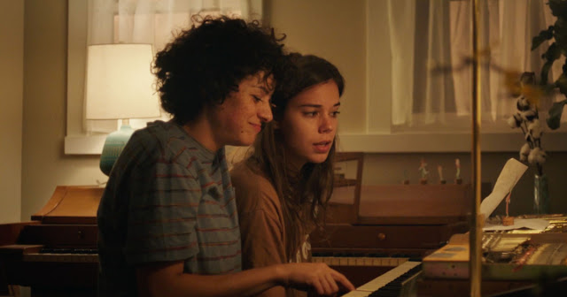 A film still from Duck Butter. Two women are sat in front of a keyboard.