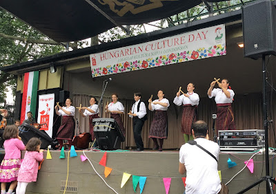 Hungarian folk singing on stage with two children watching and photographer at front of stage