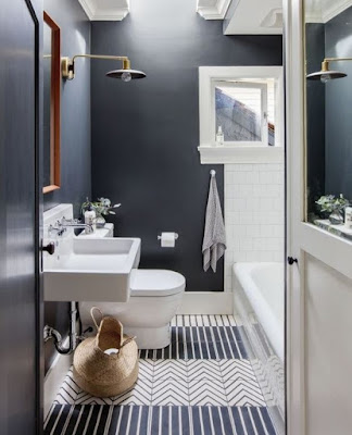 Gray bathroom design features stripe and chevron floor tiles wood framed wall mirror and wall sconce light