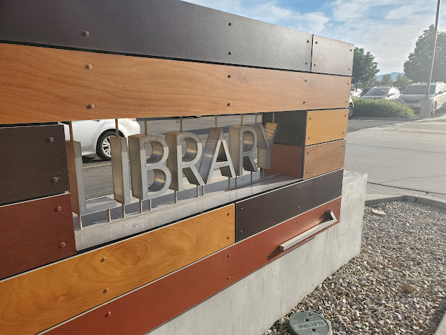 Library sign that has library written in metal cut out letters and is surrounded by wood panels