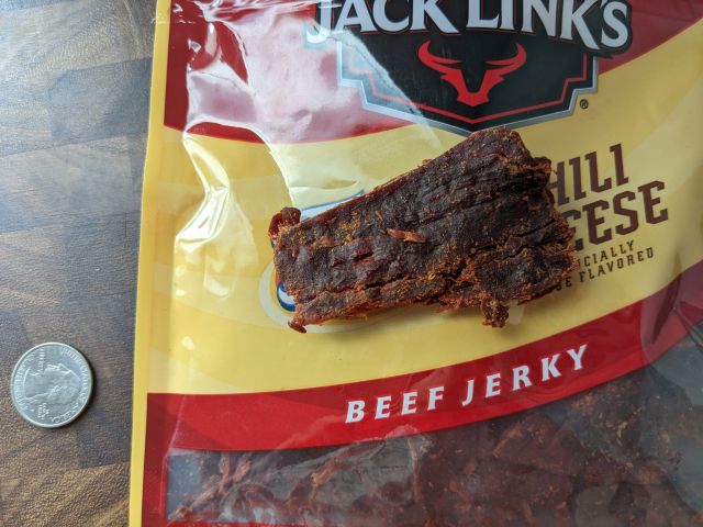 Jack Link's Fritos Chili Cheese Beef Jerky next to a quarter.