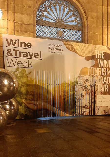 Cartaz da entrada do evento Wine & Travel Week e 3 bolas de prata