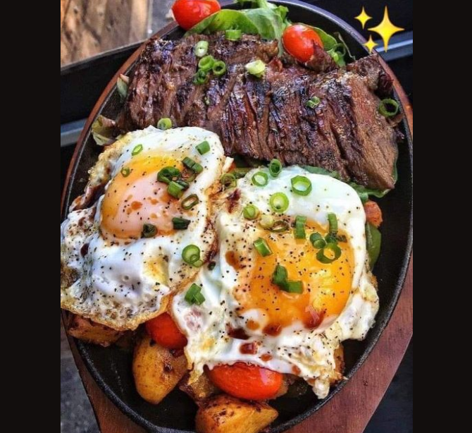 This dish appears to be a savory and hearty breakfast or brunch meal featuring steak, eggs, roasted vegetables, and fresh greens. Here's a breakdown of the ingredients and a suggested way to cook it: