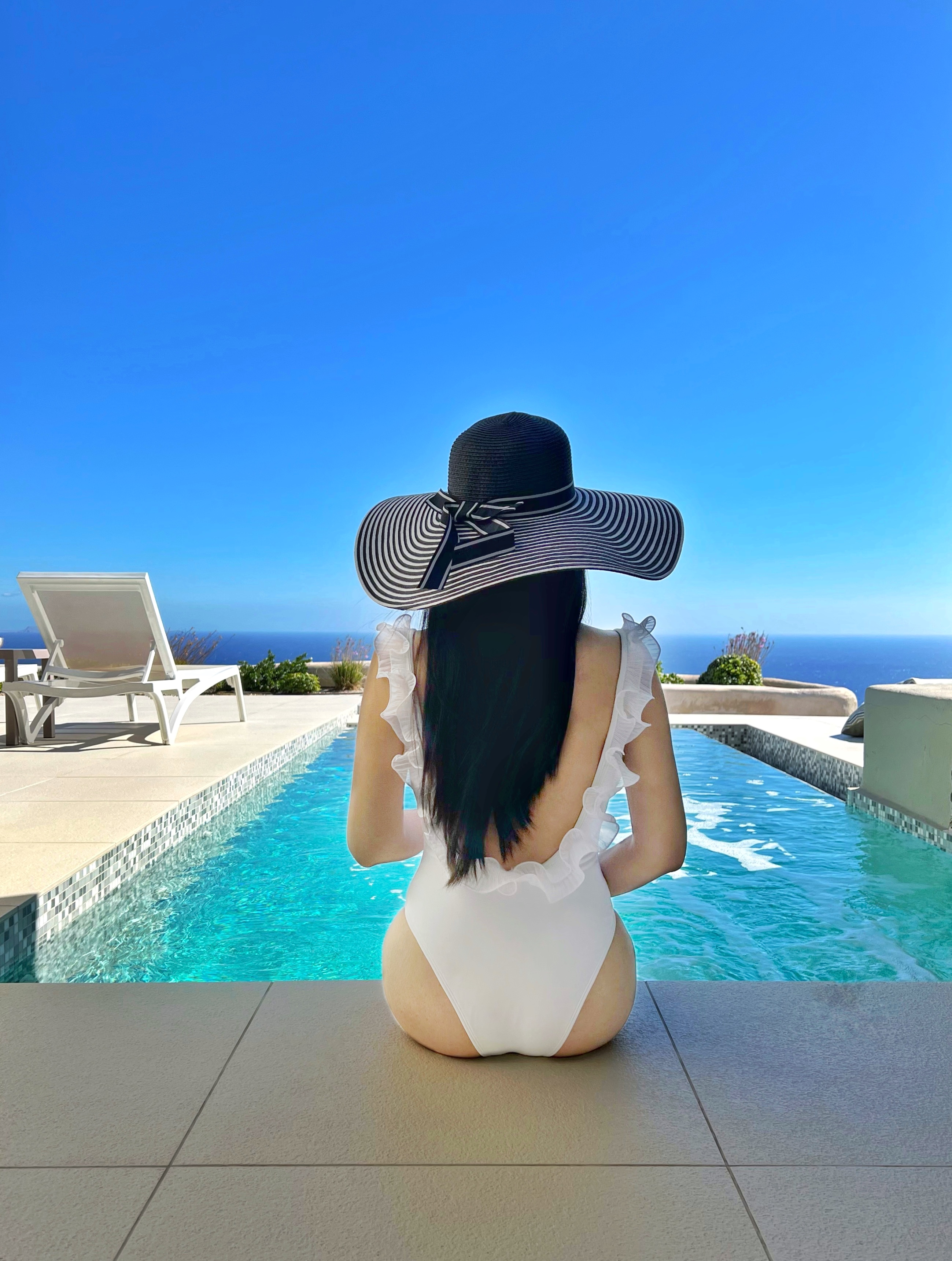 Adrienne Nguyen_Santorini Hotel_Vacation to Greek Islands_White One PIece Bikini with Ruffles and a Black Floppy Hat_Private Pool_Island Living_Mardanza Exclusive Deluxe Private Villa with Pool and Sea View