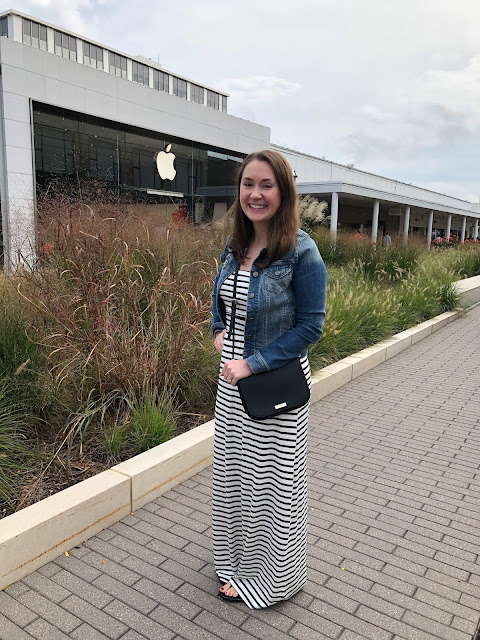 Model is wearing a black and white striped maxi dress with a denim jacket and simple black accessories.