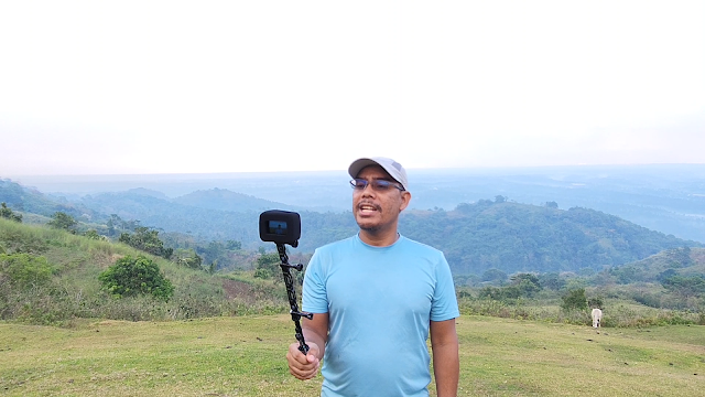 Man vlogging at the scenic hills using GoPro and selfie stick