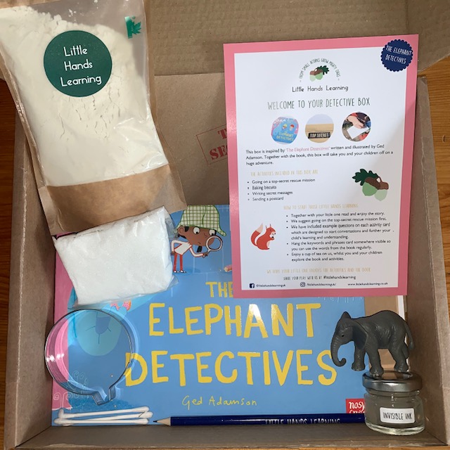 Cardboard box containing a book, biscuit mix and cutter, pencil, and elephant toy