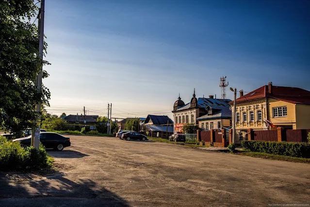 Площадь, припаркованные машины и два здания