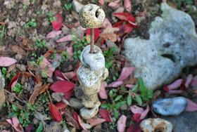 stones piled on a stick with autumn leaves around it