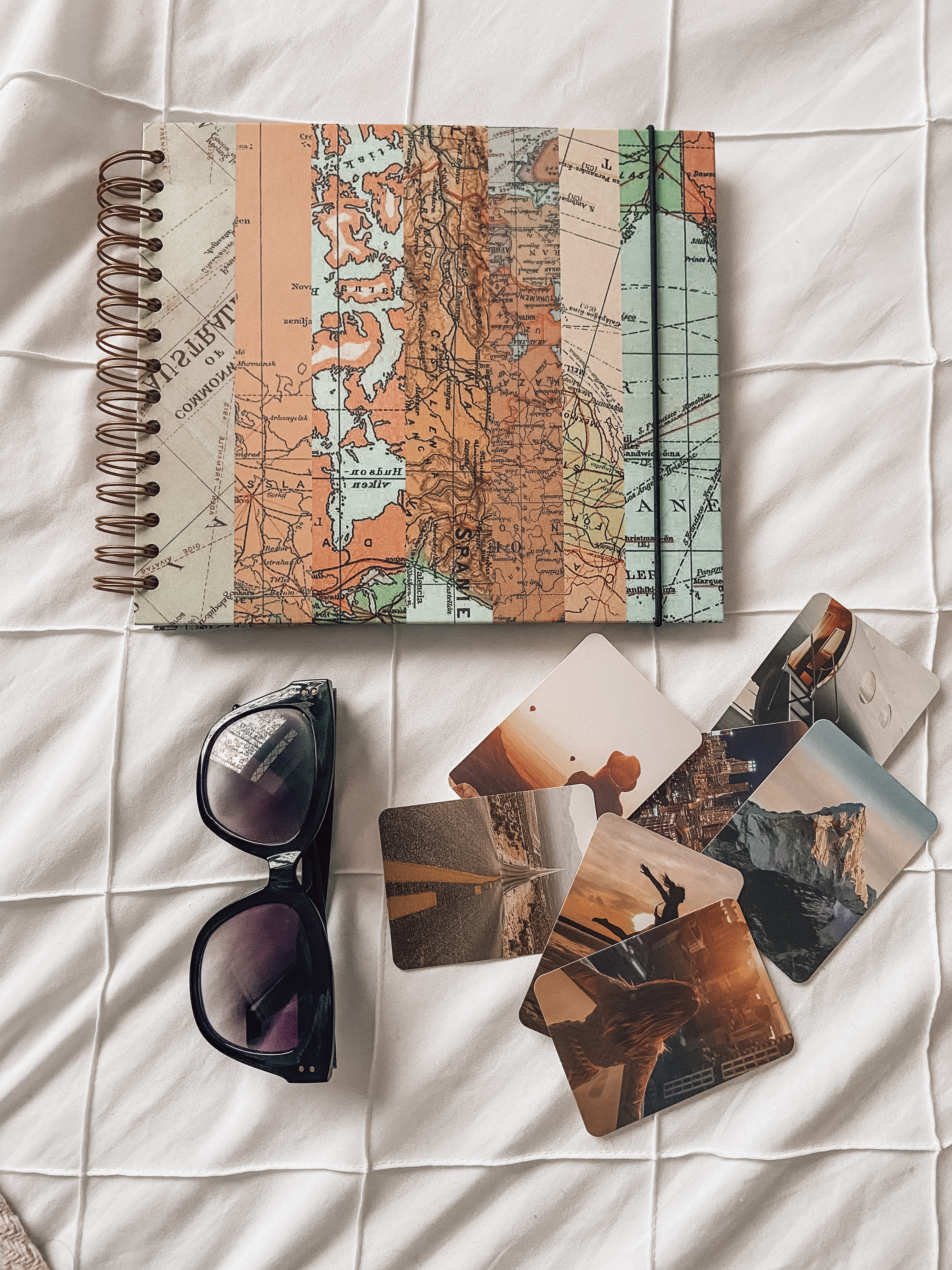 A scrapbook, a pair of black sunglasses and travel-themed photos.