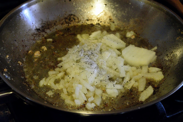 The diced onion in the skillet on the stove with salt and pepper in it.  