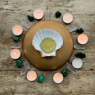 White shell surrounded by lit tealights and green malachite crystals