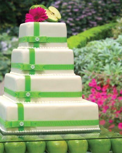 Four tier white square wedding cake with green ribbons and fuchsia gerbera