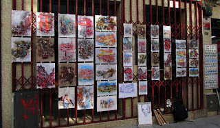 Pinturas penduradas em porta de loja da Rua das Flores