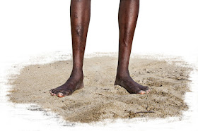 African's feet and lower legs standing on barren land