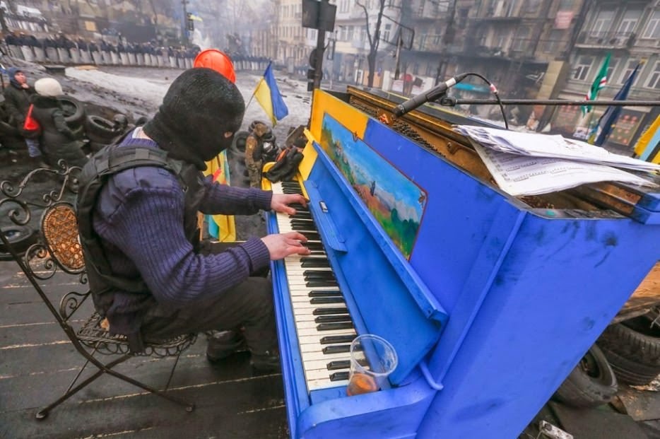 Protester plays piano over the sounds of chaos, with riot police in the backdrop. - The 63 Most Powerful Photos Ever Taken That Perfectly Capture The Human Experience
