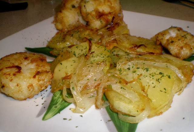 merluza frita al ajo y perejil con guarnición de patatas panaderas y cebolla