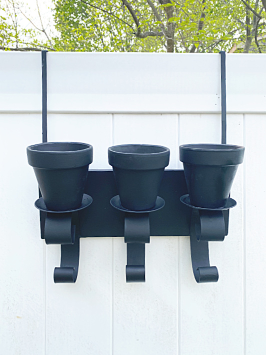 black pots on candle holder on the fence