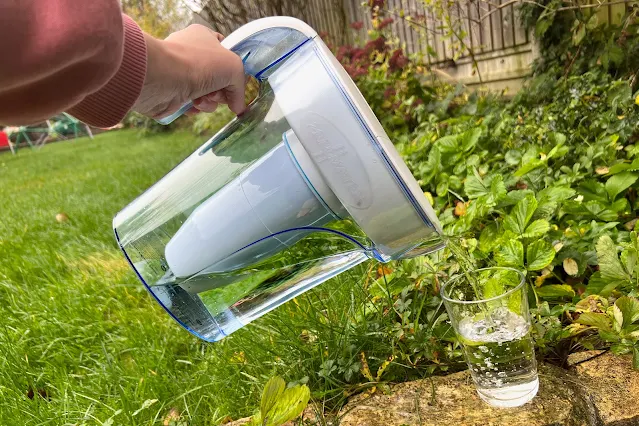 Pouring water from a ZeroWater jug into a glass in the garden