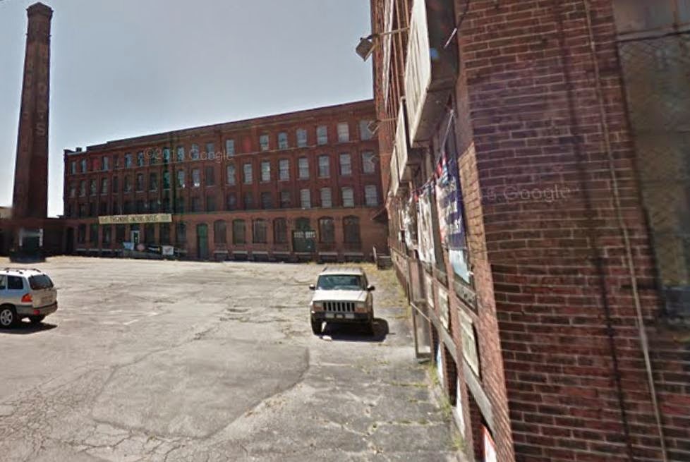 Google Street View shows parking lot, chimney and red brick facade of C.I. Hood's Laboratory (factory)