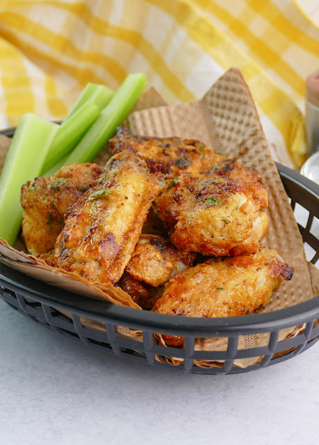 wings in a black plastic basket with celery on the side.